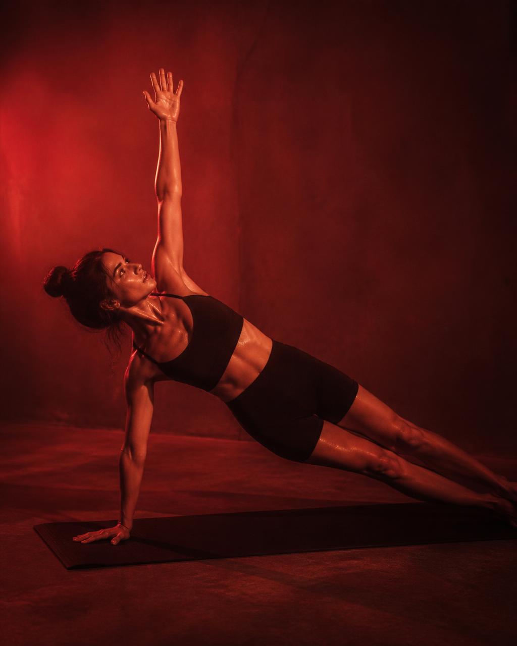 Práctica de pilates en mat con luz cálida roja en un estudio con calor
